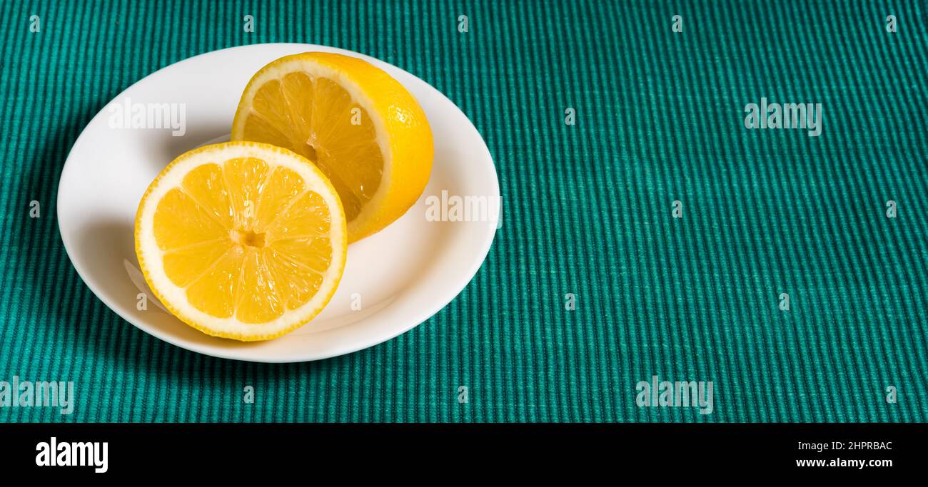 un limone succoso tagliato su un piatto su uno sfondo tessile verde, spazio copia, spazio per il layout del testo Foto Stock