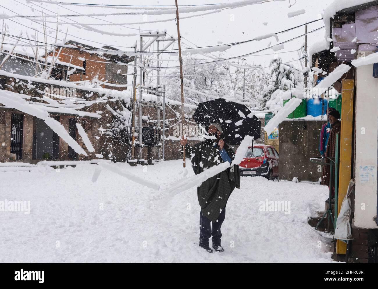 Kashmir, India , 23/02/2022, Srinagar, India. 23rd Feb 2022. Un uomo libera la neve dai fili durante la nevicata pesante in Srinagar.la valle del Kashmir il mercoledì mattina svegliato ad una coperta pesante della nevicata che ha interrotto la vita normale della gente. Le operazioni di volo, il trasporto di superficie e le attività di routine della vita si sono arrestate. Credit: SOPA Images Limited/Alamy Live News Foto Stock