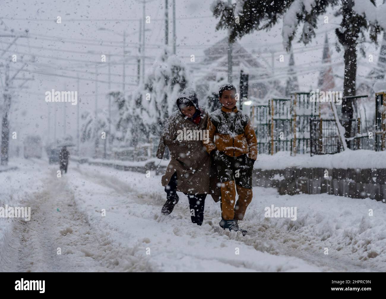 Kashmir, India , 23/02/2022, Srinagar, India. 23rd Feb 2022. I bambini camminano attraverso una strada coperta di neve durante le pesanti nevicate a Srinagar.la valle del Kashmir il mercoledì mattina svegliarsi ad una coperta pesante di nevicate che ha interrotto la vita normale della gente. Le operazioni di volo, il trasporto di superficie e le attività di routine della vita si sono arrestate. Credit: SOPA Images Limited/Alamy Live News Foto Stock