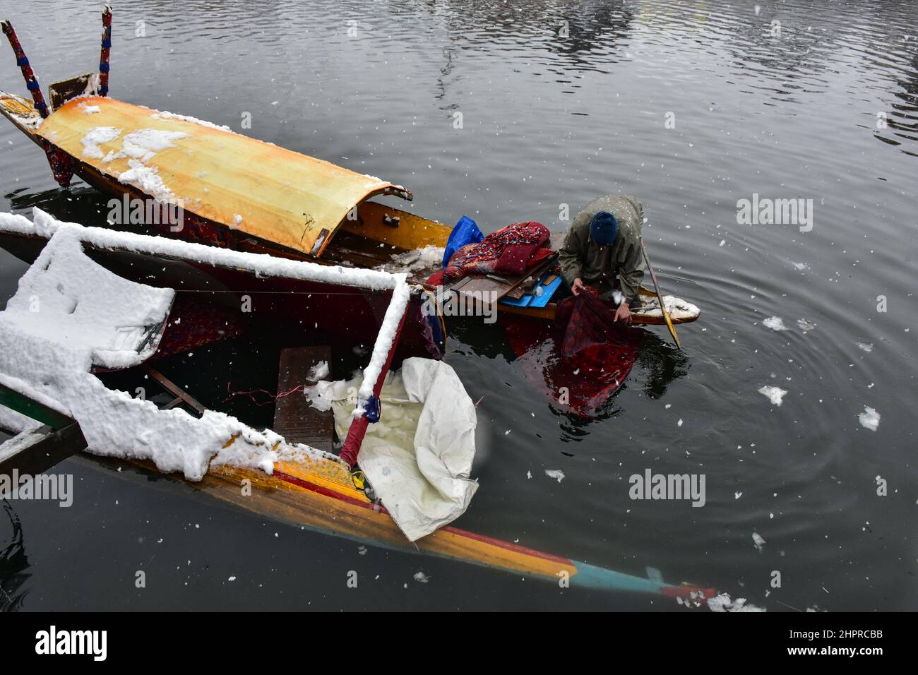 Kashmir, India , 23/02/2022, Srinagar, India. 23rd Feb 2022. Un uomo ispeziona la sua barca danneggiata a causa di pesanti nevicate in Srinagar.la maggior parte delle aree della valle del Kashmir il mercoledì ha ricevuto nevicate - la prima caduta pesante della stagione nelle pianure - interrompendo il volo e le operazioni ferroviarie e portando alla chiusura della vitale Srinagar-Jammu strada nazionale, funzionari qui ha detto. Credit: SOPA Images Limited/Alamy Live News Foto Stock