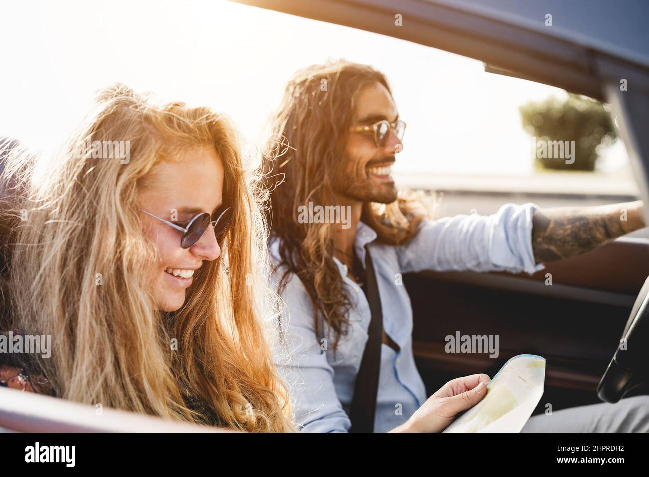 Giovane coppia che si diverte utilizzando la mappa all'interno di un'auto convertibile durante le vacanze estive - Focus on girl hand Foto Stock