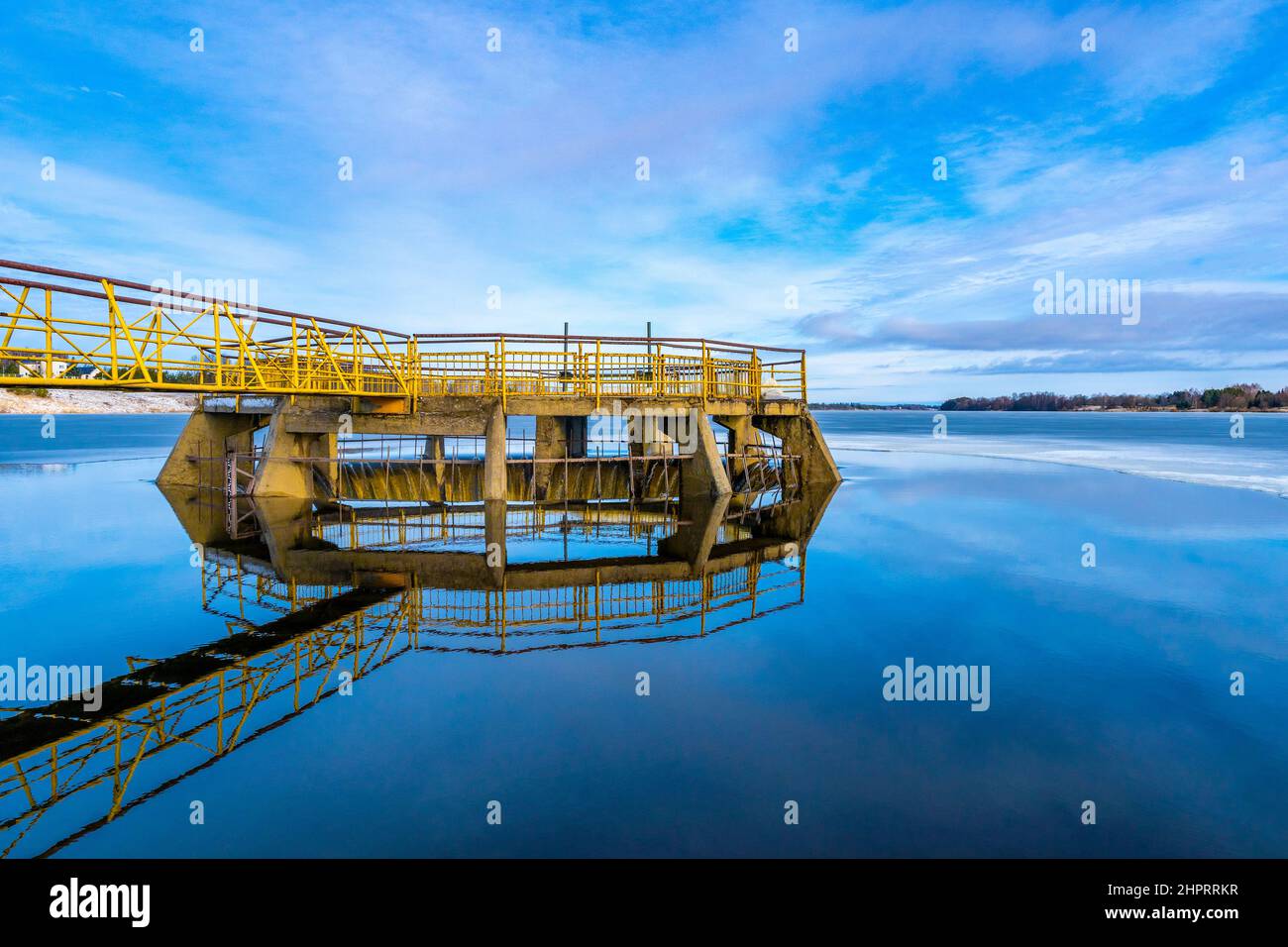 Diga di fiume e canale giallo con riflessione sull'acqua Foto Stock