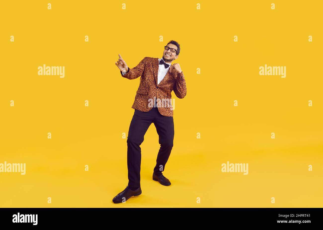 Felice allegro ragazzo nero giovane in giacca da festa ballando isolato su sfondo giallo Foto Stock