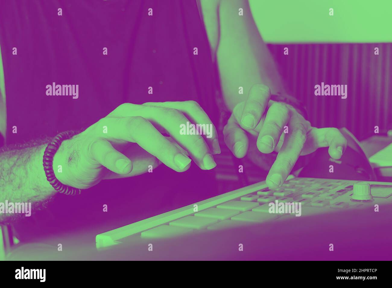 vista laterale del giovane caucasico che batte su un controller midi, producendo e componendo musica elettronica e musica urbana commerciale. Foto Stock