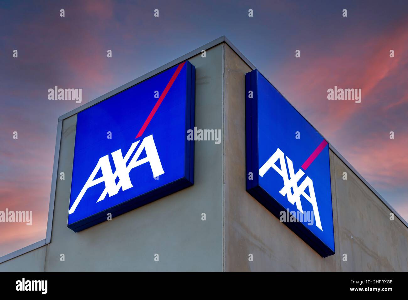 Fossano, Italia - 22 febbraio 2022: Logo AXA su cartelli illuminati su un edificio colorato dopo il tramonto, Axa è assicurazione francese e servizi bancari Foto Stock