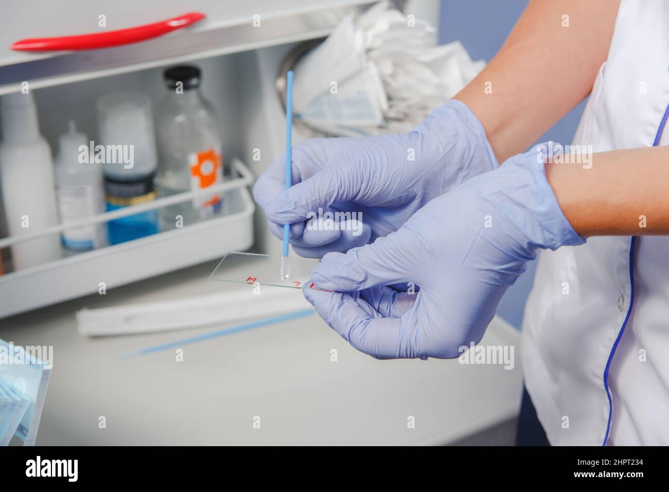 Primo piano di un medico o di un infermiere in guanti protettivi che tengono sotto microscopio il vetro per analisi di ricerca di materiali biologici Foto Stock