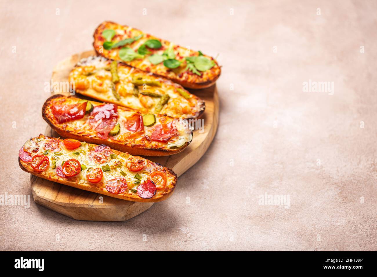 Fette di pizza sul pane con formaggio e ingredienti come salame, prosciutto, prosciutto. Vista laterale con spazio di copia Foto Stock