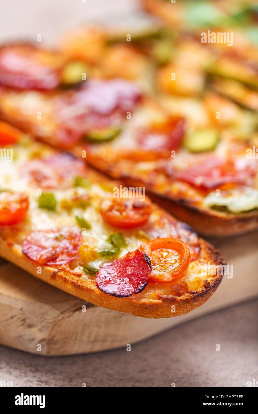 Fette di pizza sul pane con formaggio e ingredienti come salame, prosciutto, prosciutto. Messa a fuoco selettiva Foto Stock