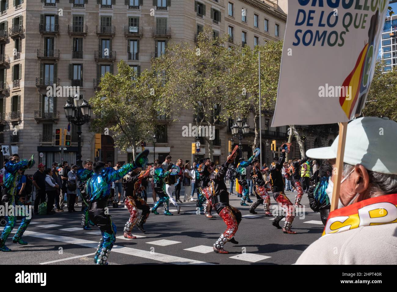 Ragazzi boliviani che si esibiscono su strada durante dia de la Hispanidad in Gracia Avenue a Barcellona, Spagna. Persone con bandiere e bandiere. Foto Stock