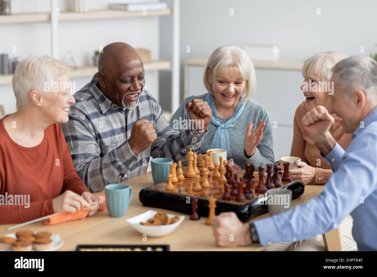 Gruppo emozionale multietnico di persone anziane che giocano a scacchi Foto Stock
