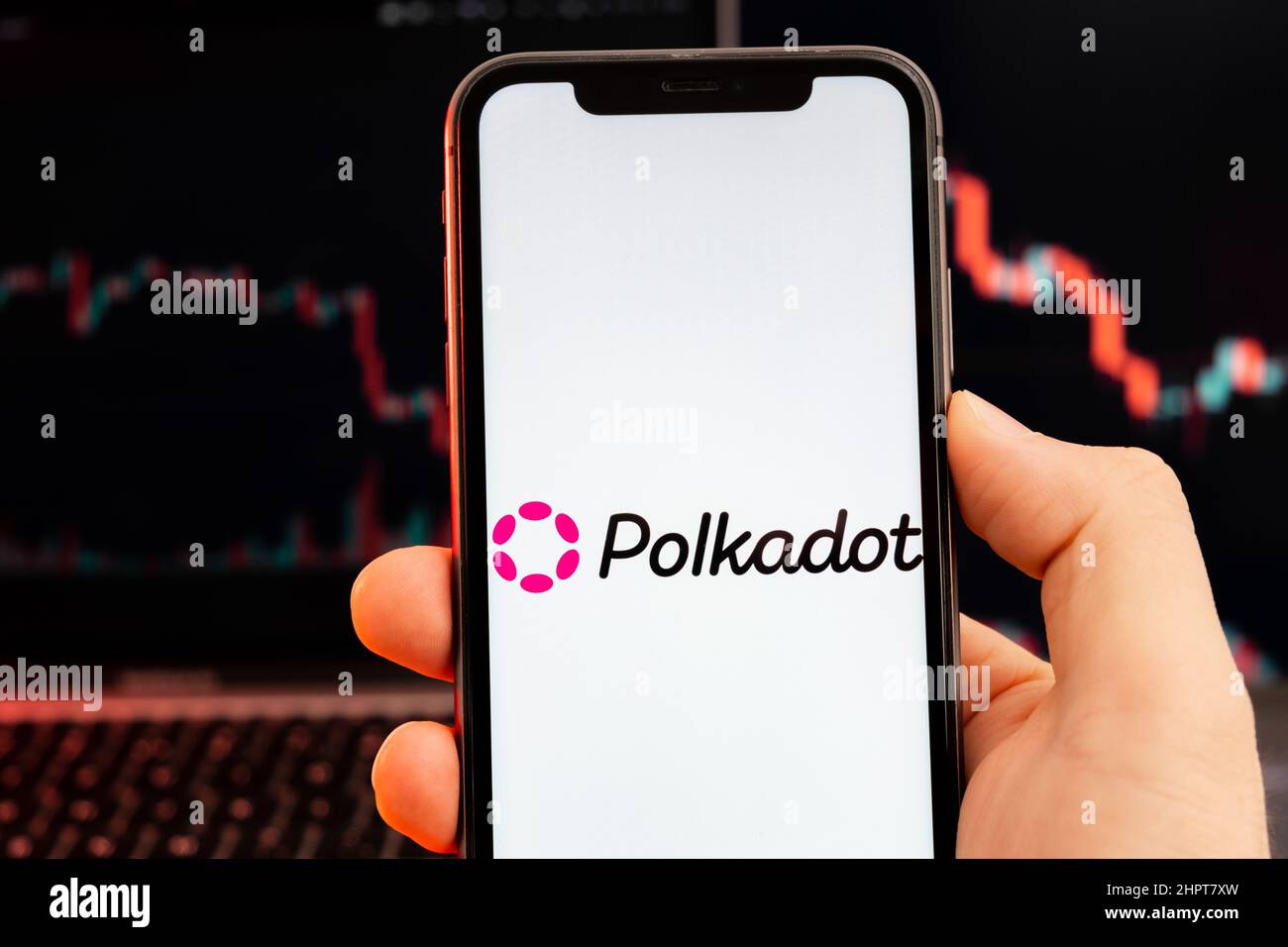 Polkadot DOT logo criptovaluta sullo schermo di smartphone in mano mans con downtrend in classifica su sfondo rosso, febbraio 2022, San Francisco, USA. Foto Stock