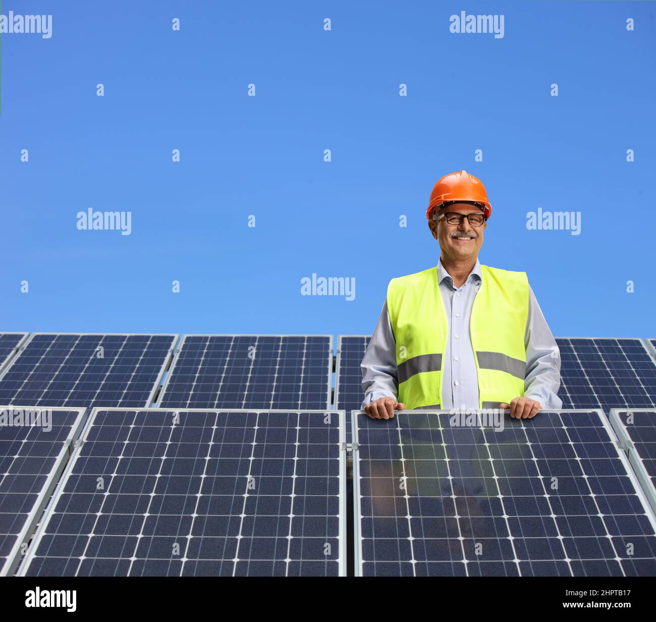 Ingegnere in piedi dietro i pannelli solari e sorridente Foto Stock