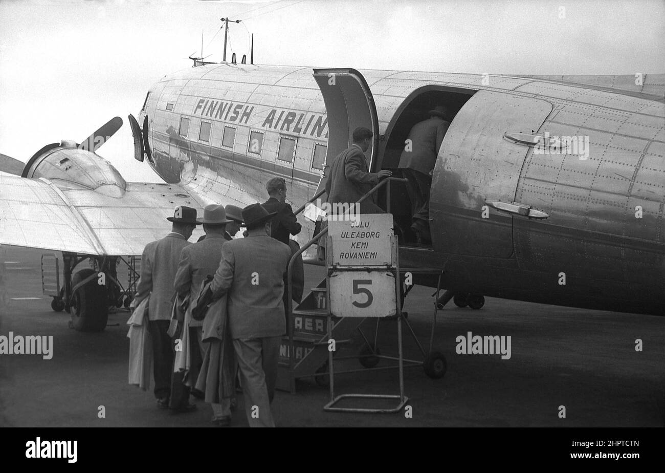 1940s, passeggeri maschi storici, diversi cappotti impermeabili e cappelli, imbarco su un velivolo Douglas DC-3 della Finnish Airlines, all'aeroporto di Helsinki, Finlandia. Foto Stock
