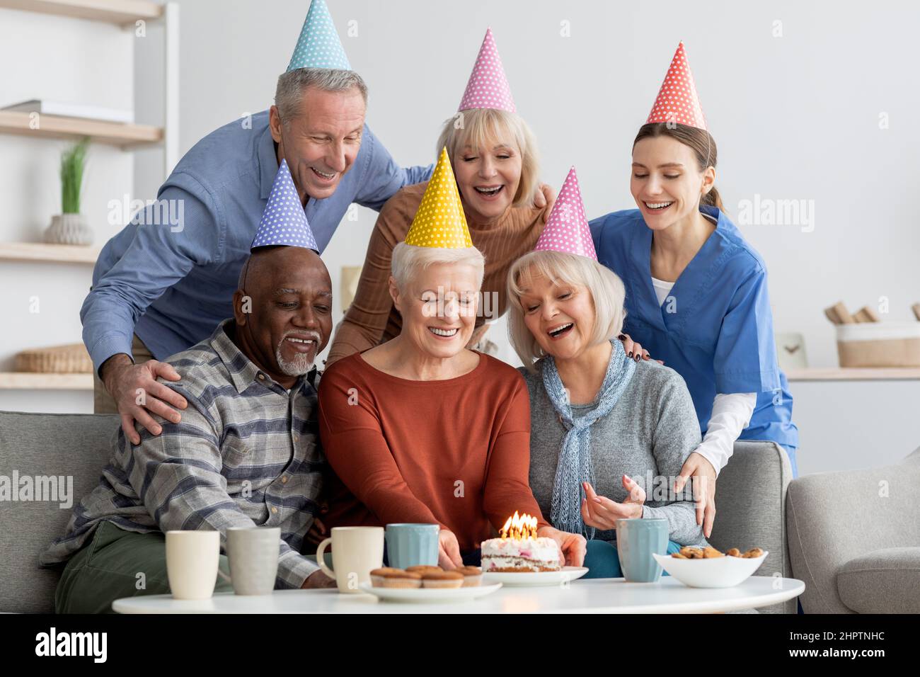Ritratto di gruppo degli anziani e dell'infermiera che festeggia il compleanno Foto Stock