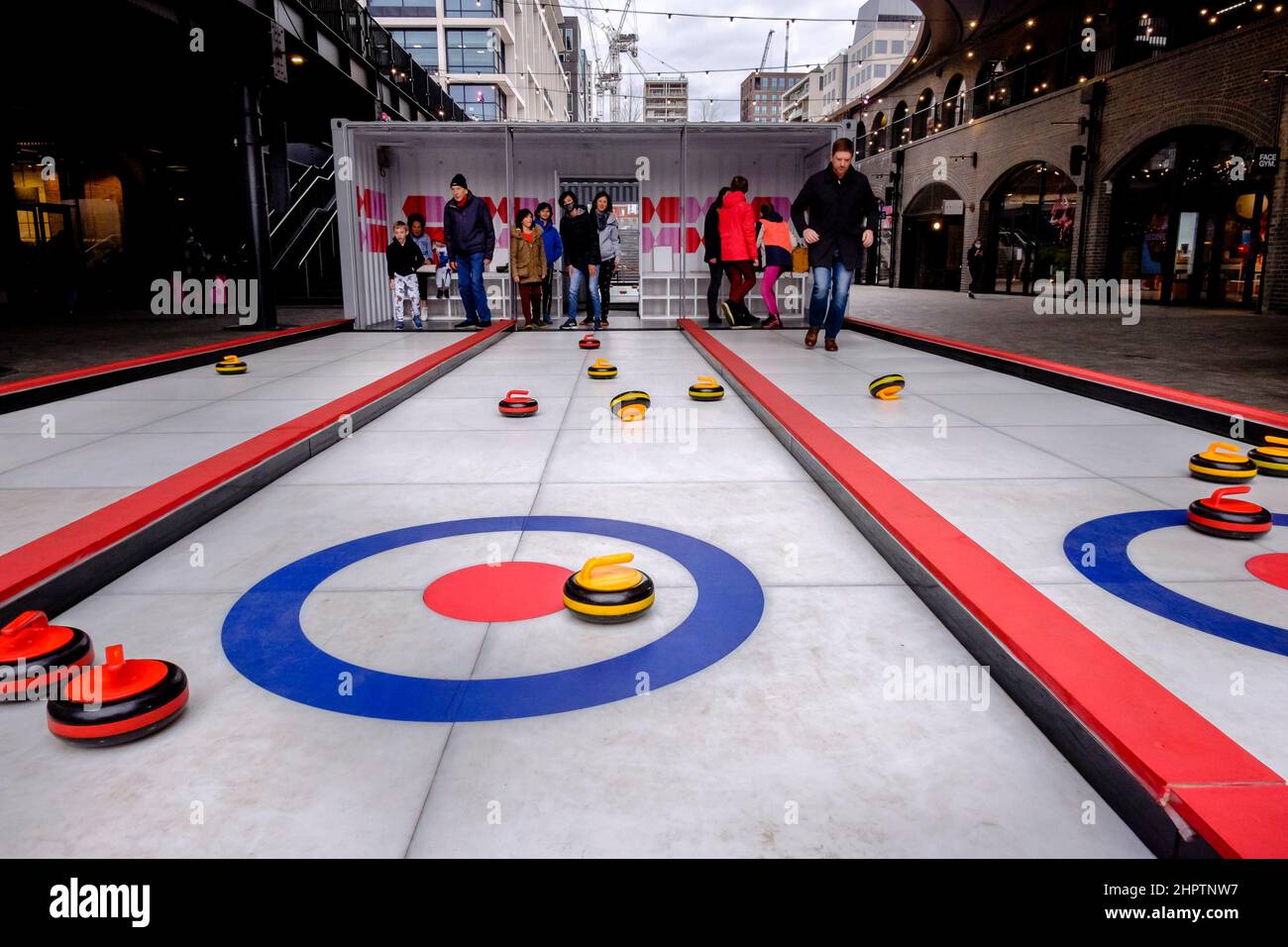 Dopo il successo del Team GB nell'evento di curling alle Olimpiadi invernali del 2022, i membri del pubblico provano una versione su ghiaccio artificiale dello sport, Londra, Regno Unito. Foto Stock