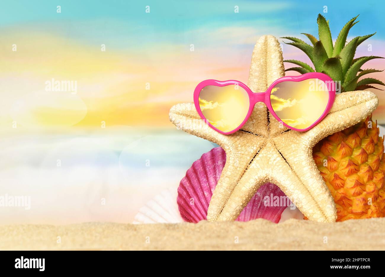 Mare tropicale estivo con ananas, stelle marine e occhiali da sole sulla spiaggia di sabbia calda. Concetto di viaggio e vacanza con spazio copia. Foto Stock