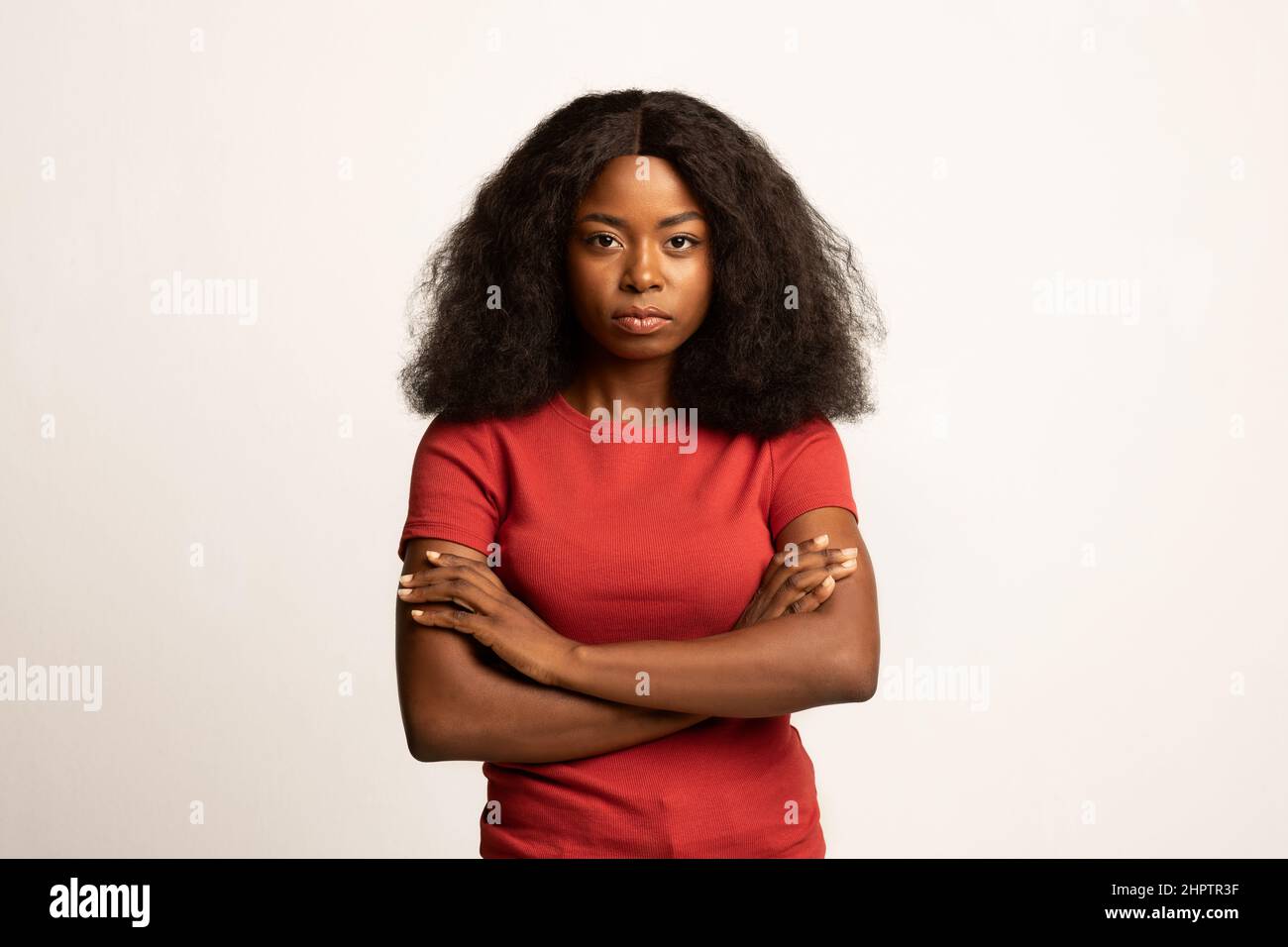 Ritratto di una giovane donna afroamericana seria in piedi con le braccia ripiegate Foto Stock