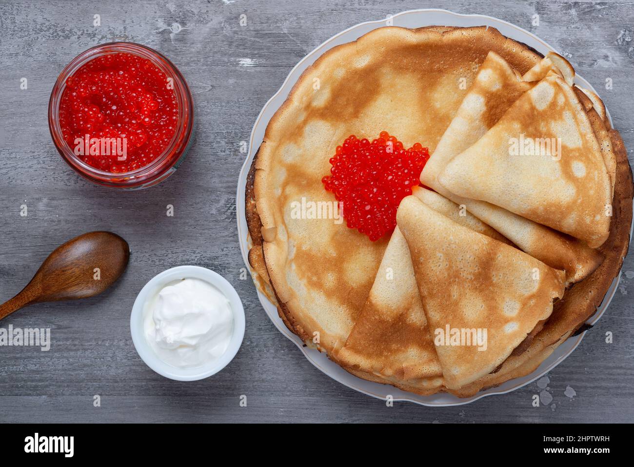 Impila di sottili pancake frullati con caviale rosso e panna acida fresca Foto Stock