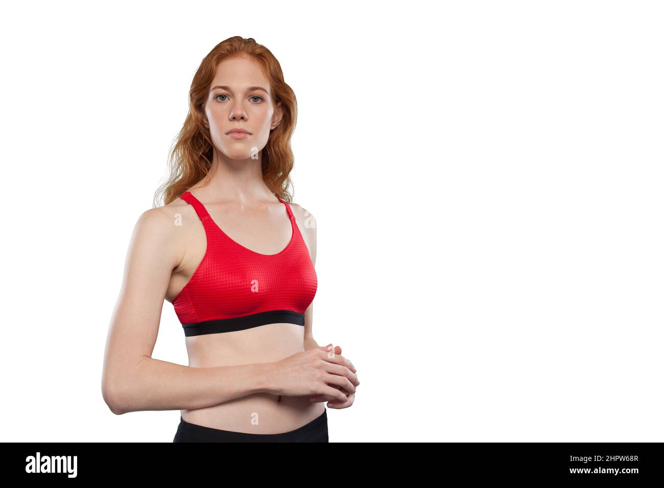 L'atleta femminile si pone su uno sfondo bianco. Ritratto da studio di donna che indossa il canotta rosso sportivo. Essere come look eroe Foto Stock