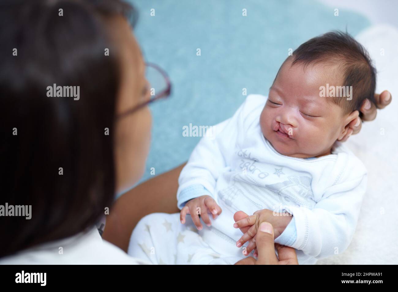 Trovare conforto tra le braccia della madre. Scatto di una bambina addormentata con un palato di ciglia tenuto dalla madre. Foto Stock