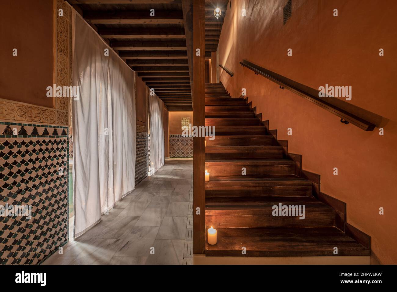 Scale e struttura in legno con candele sui gradini e archi semicircolari ricoperti di tende bianche Foto Stock