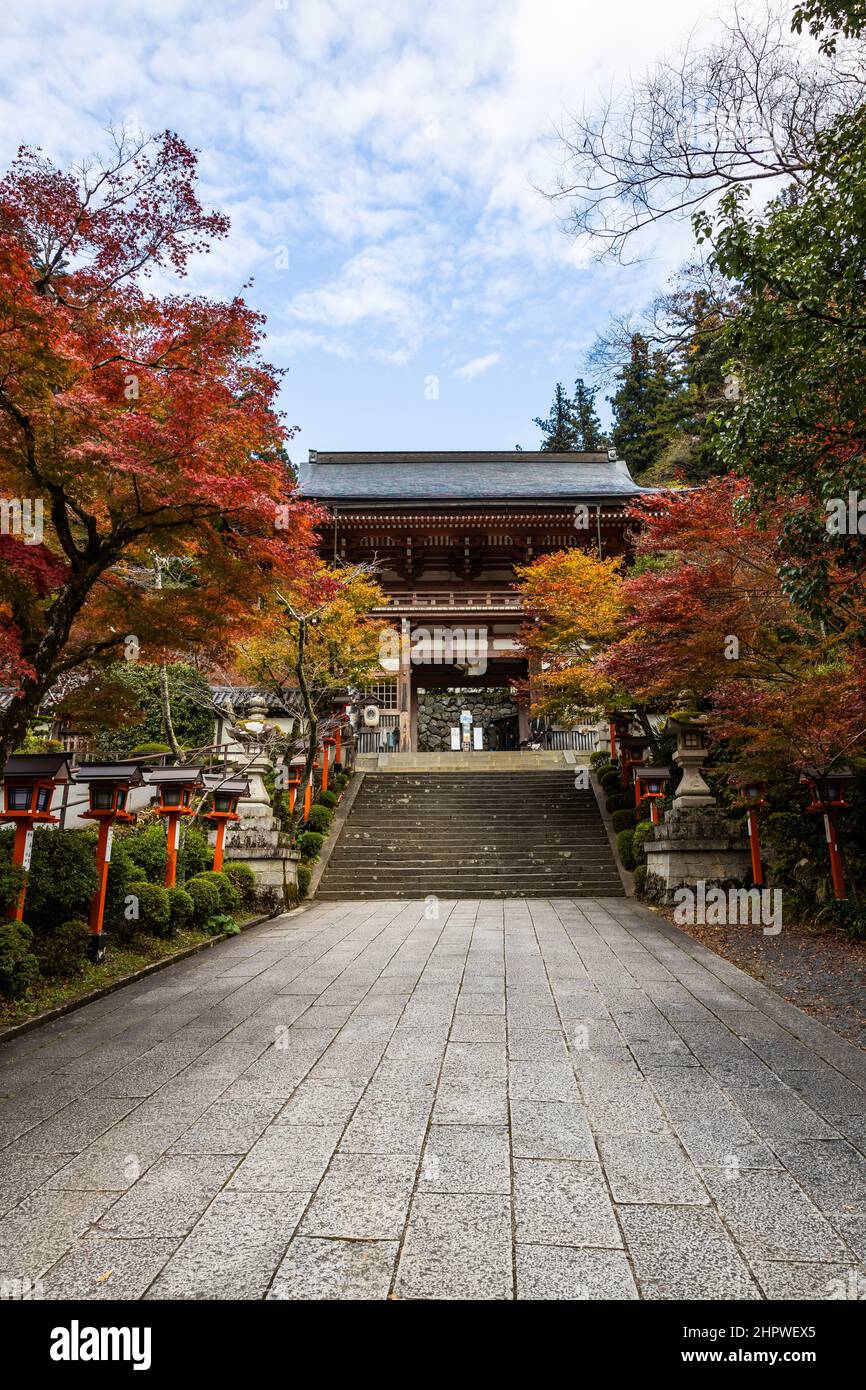 Un percorso fiancheggiato da lanterne con scale che conducono al Tempio Kurama-dere a nord di Kyoto, in Giappone, in una mattinata d'autunno. Foto Stock