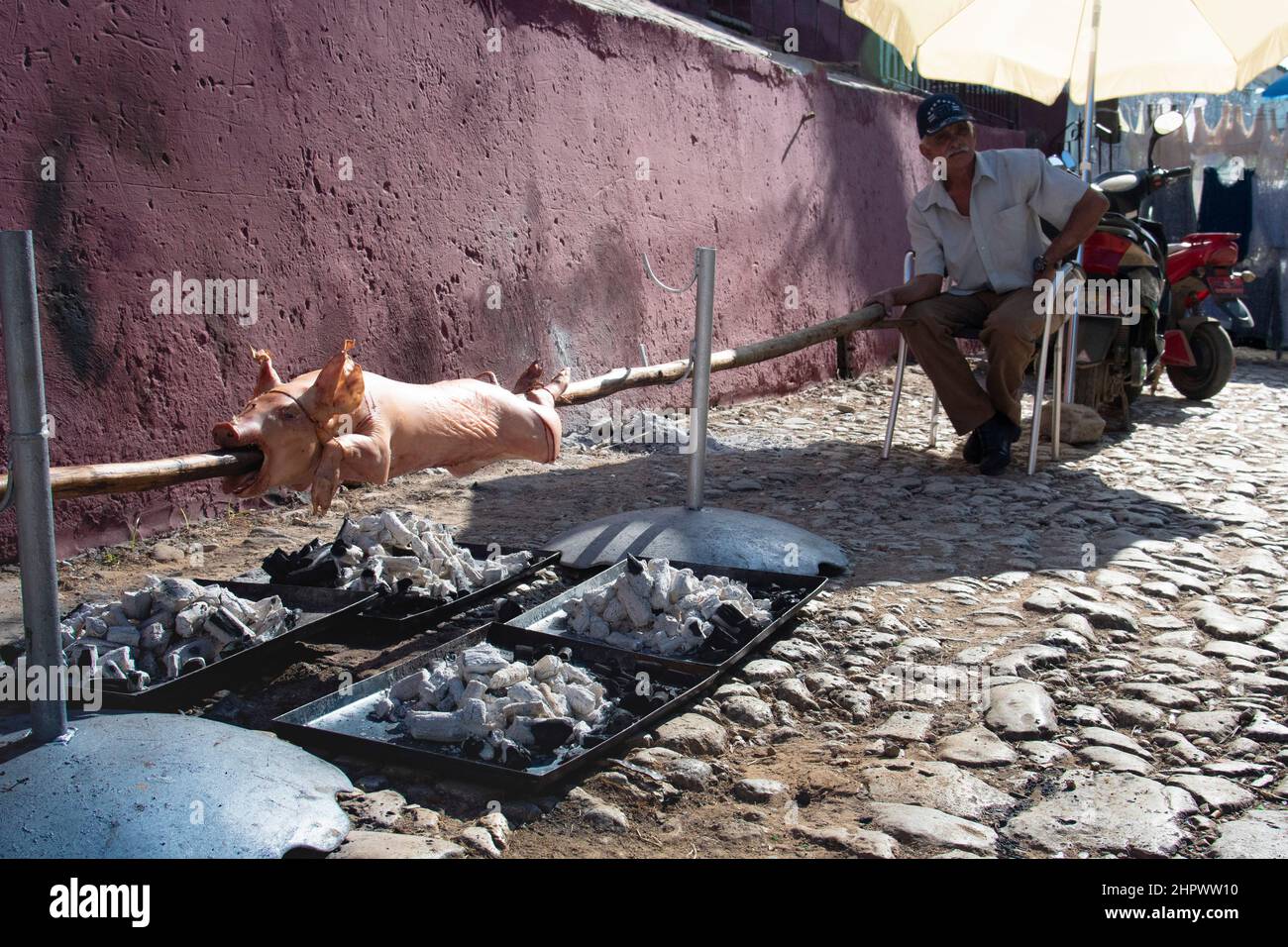 Maiale su spit che viene cucinato su carboni caldi da un uomo ad un evento per la famiglia e amico a Trinidad, Cuba. Foto Stock