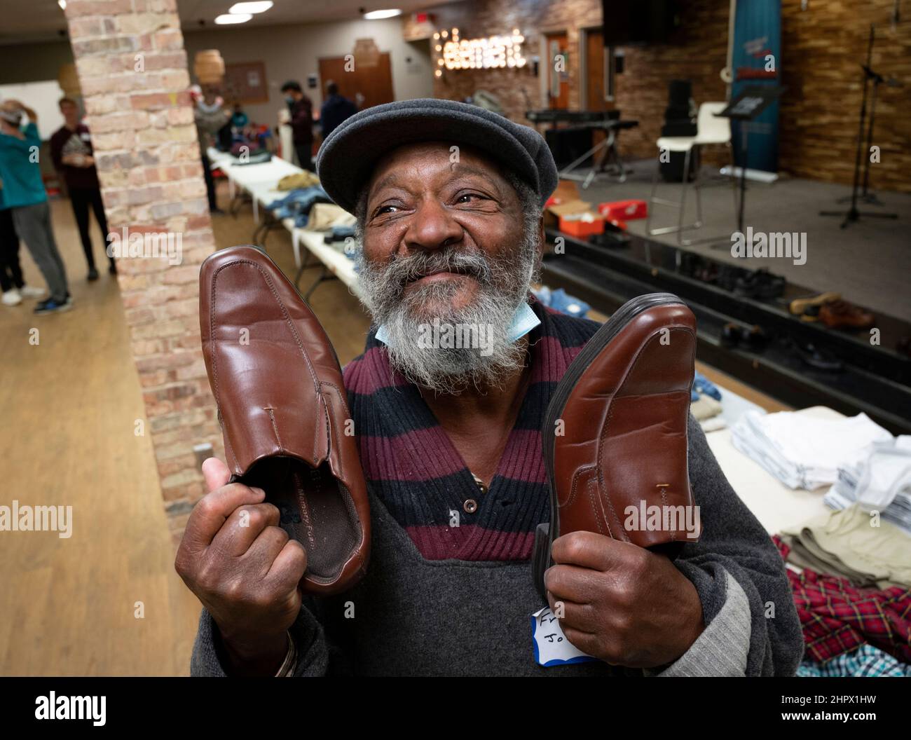 Marietta, Georgia, Stati Uniti. 13th Feb 2022. Un uomo senza tetto mostra la sua gioia a trovare un paio di scarpe da tavoli pieni di vestiti donati alla First Baptist Church di Marietta, Georgia durante una cena per individui o famiglie che stanno lottando finanziariamente o senza casa. (Credit Image: © Robin Rayne/ZUMA Press Wire) Foto Stock