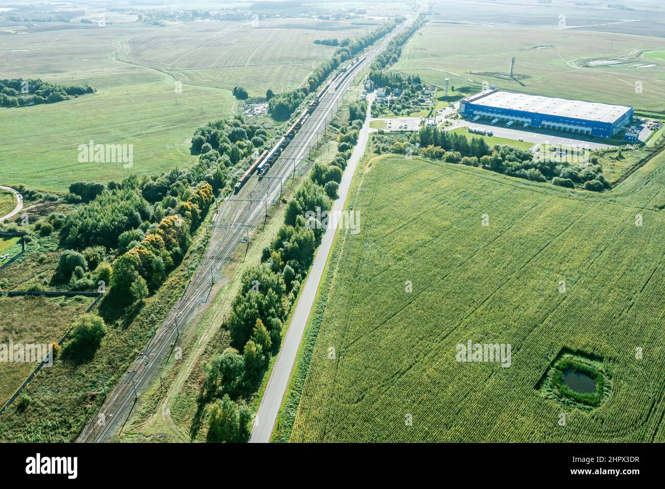 vista aerea della pista ferroviaria e centro logistico in zona rurale in giornata di sole Foto Stock