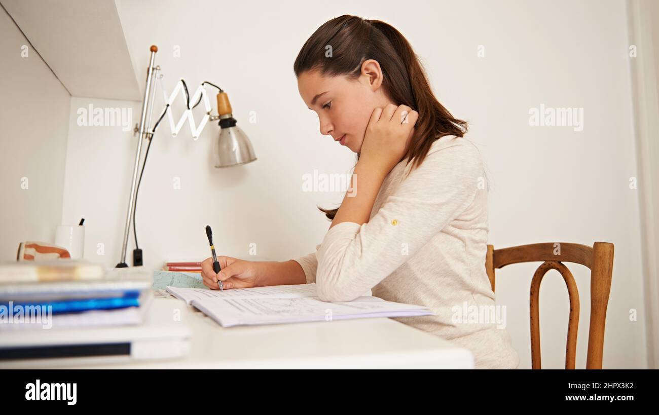 Ottenere tutto nella sua testa. Scatto di una giovane donna che studia alla sua scrivania a casa. Foto Stock