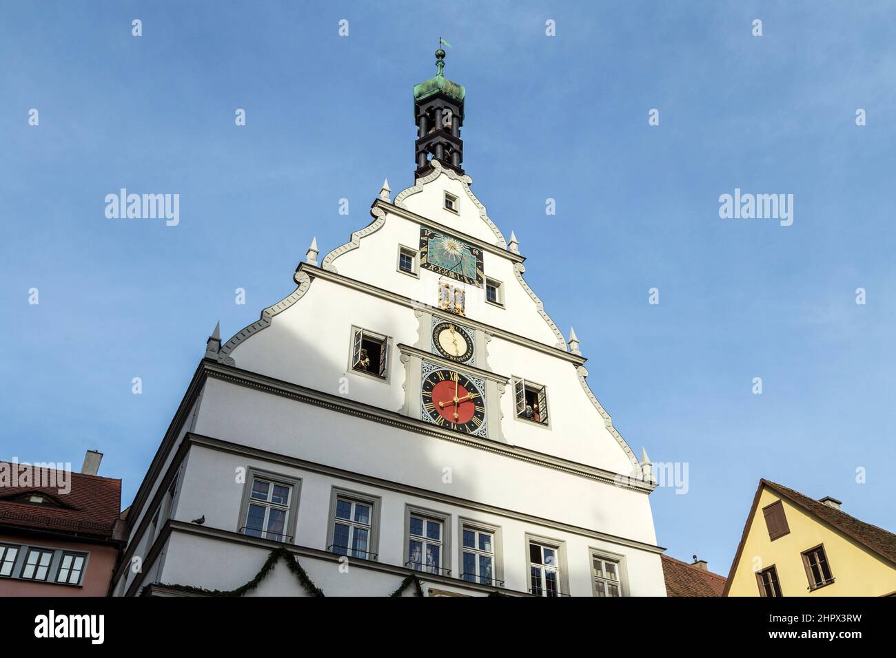 Picco di un edificio con un orologio contro un cielo blu a Rothenburg ob der Tauber, Germania Foto Stock