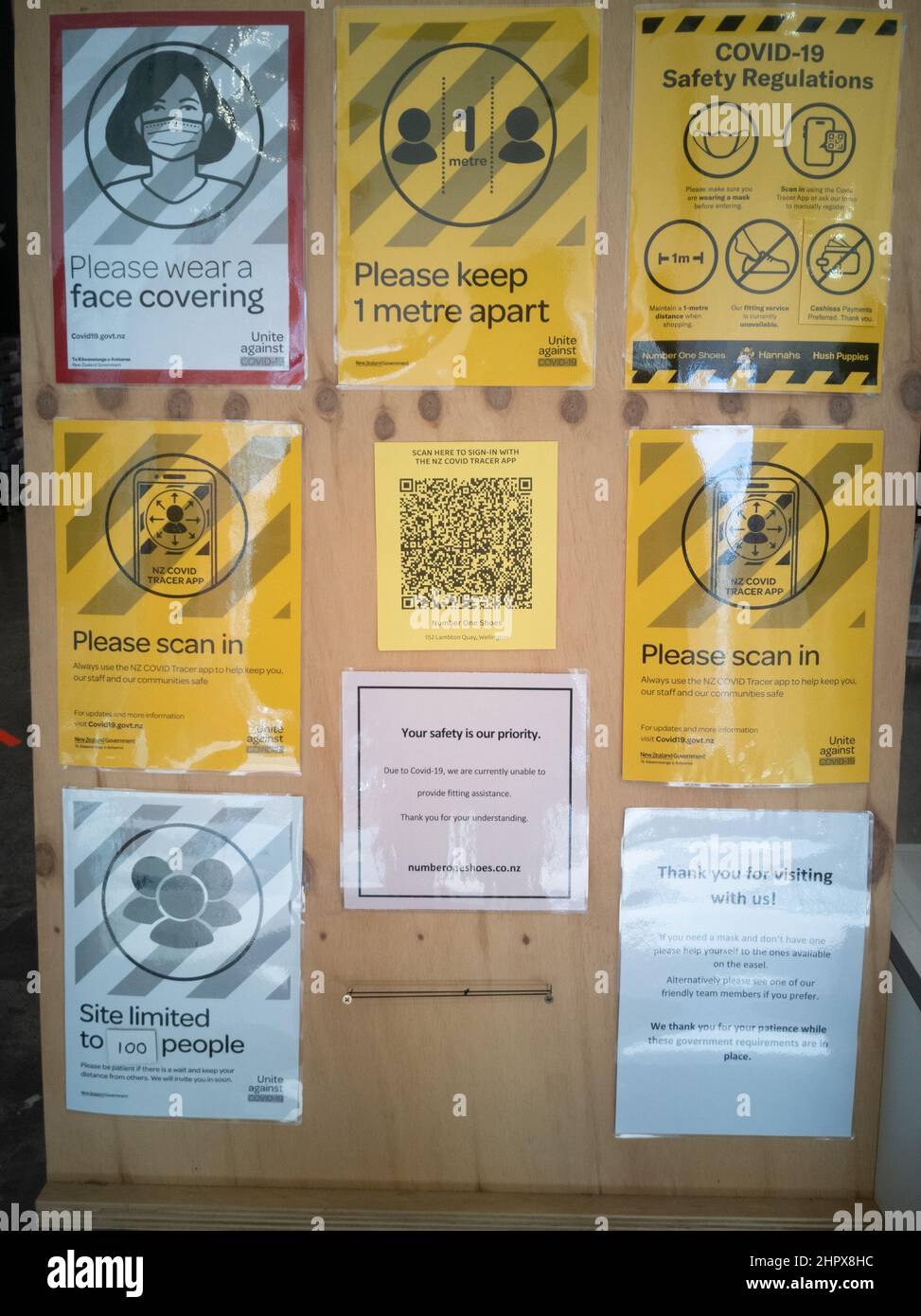 Scopri i cartelli d'ingresso con i requisiti per l'ingresso, tra cui indossare maschere facciali, distanziare e scansionare un codice QR, durante la pandemia covid Foto Stock