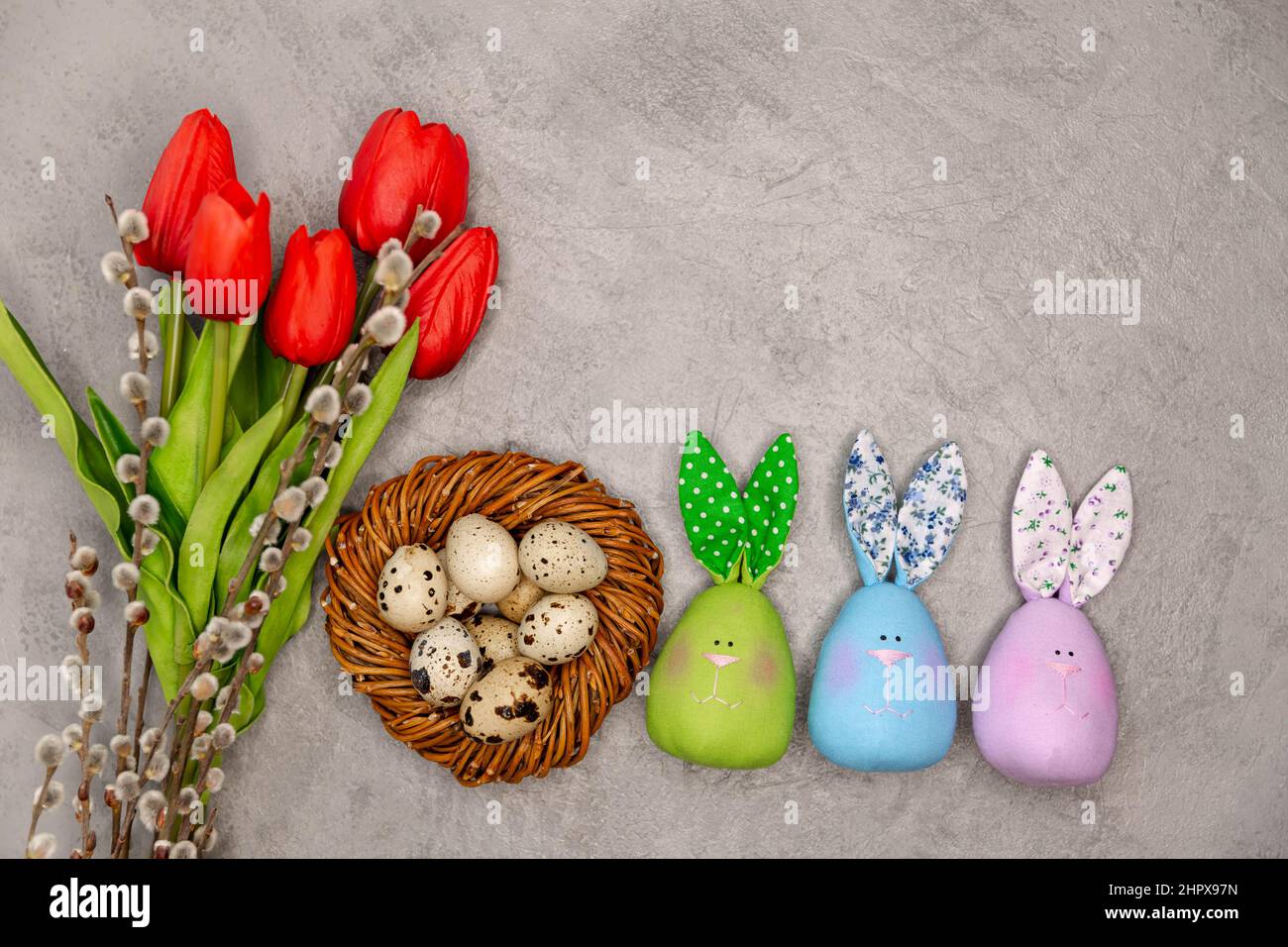 Decorazione pasquale su sfondo grigio. Fiori, uova nel nido Foto Stock