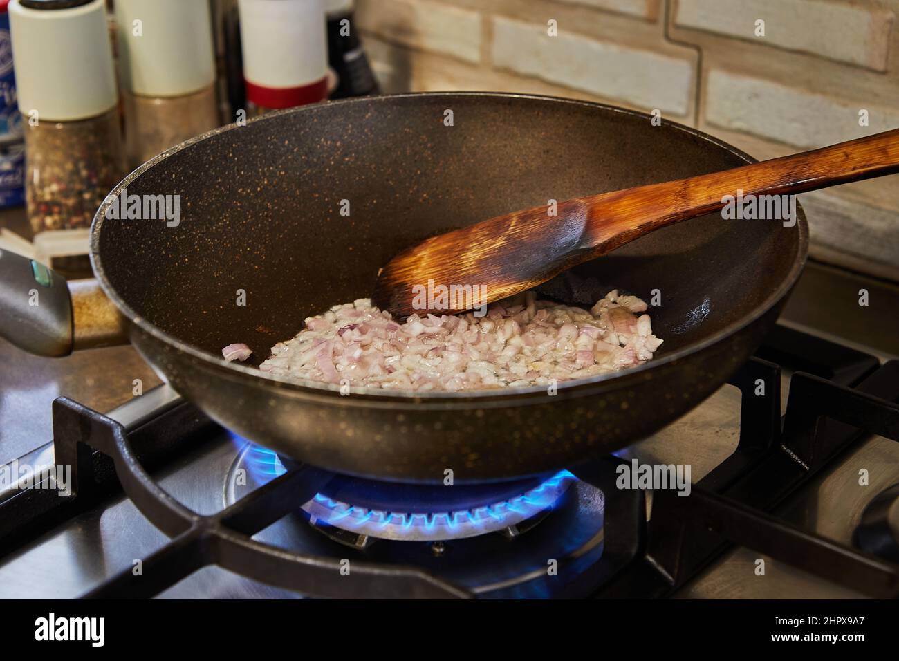 Le cipolle viola vengono fritte in una padella su una stufa a gas. Preparare gli ingredienti e le verdure prima della cottura. Foto Stock