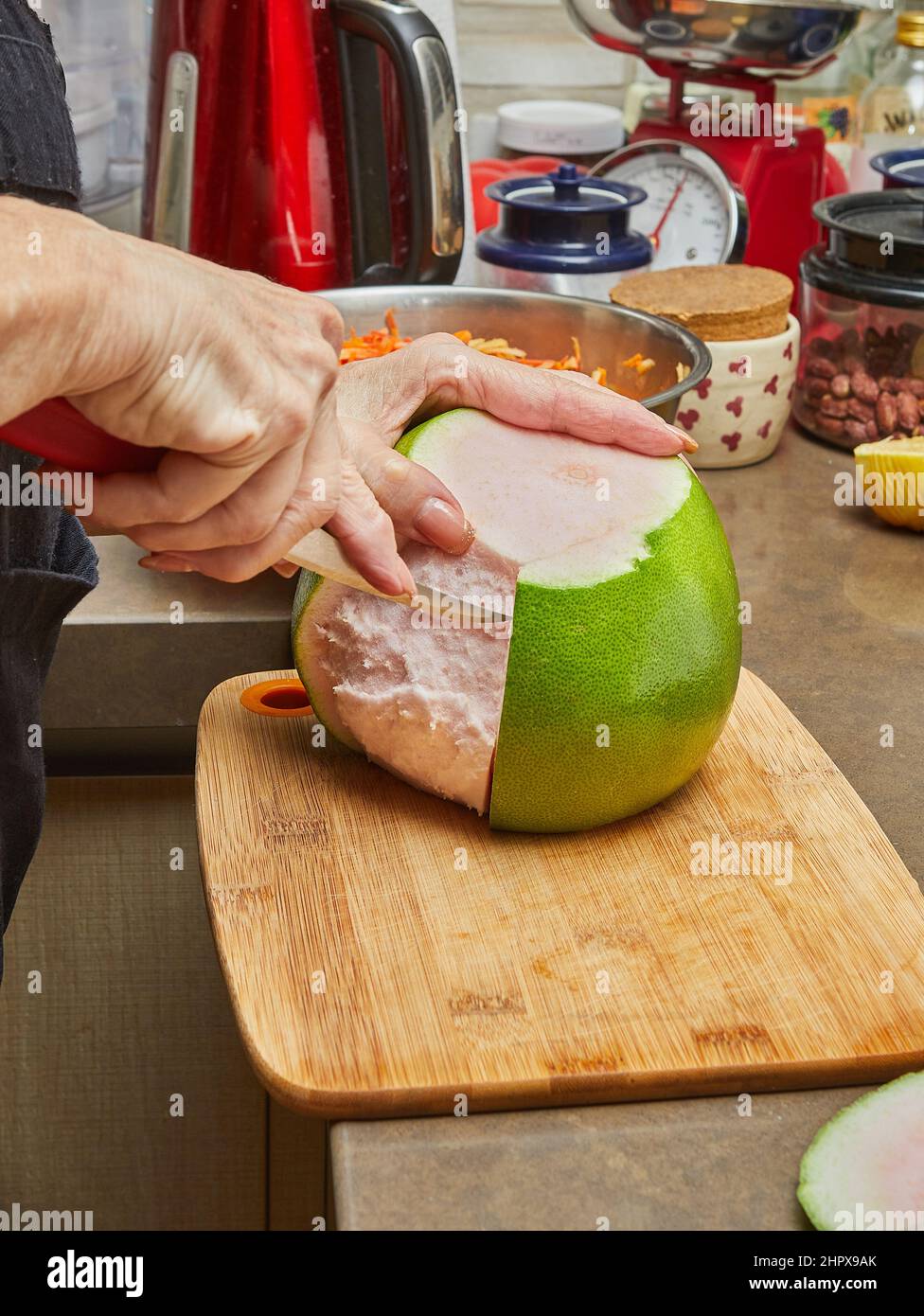 Rosso pomelo all'interno del cuoco taglia a pezzi su un tagliere. Foto Stock