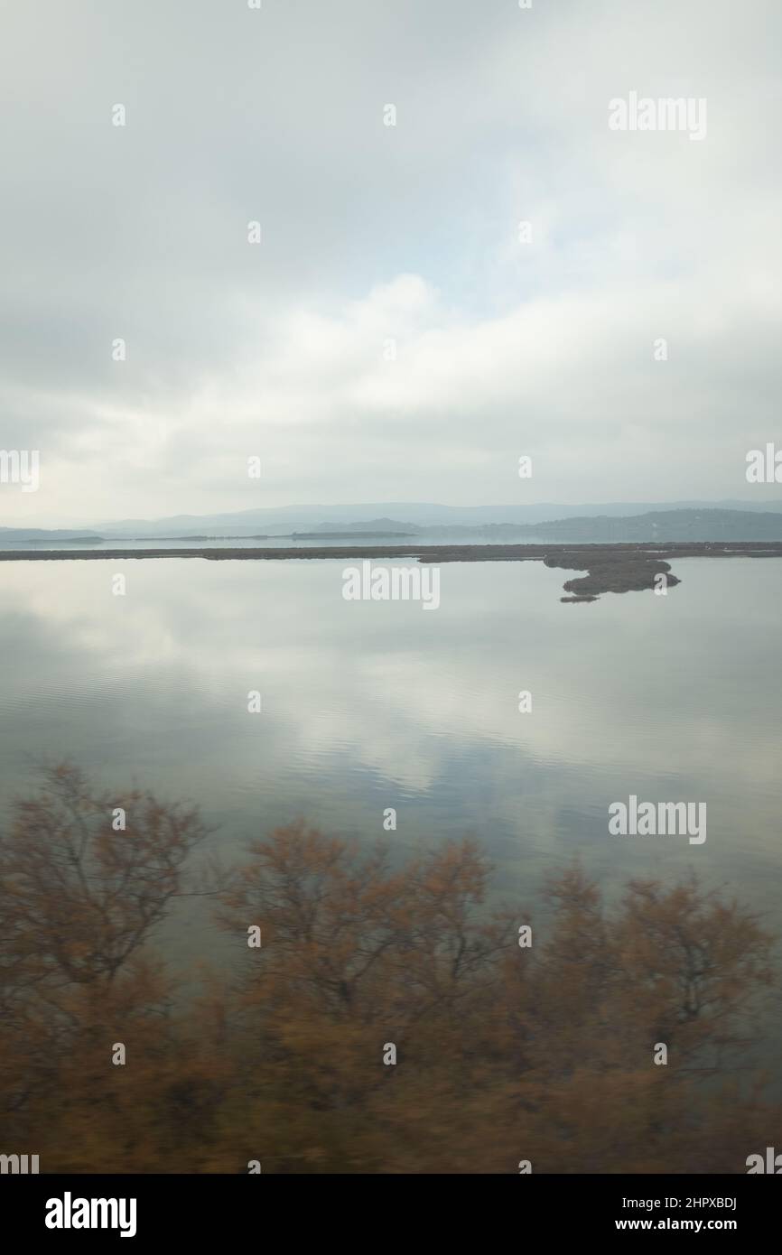 Paesaggio nuvoloso che si riflette sulle tranquille zone umide acque del lago in Camargue, Francia Foto Stock