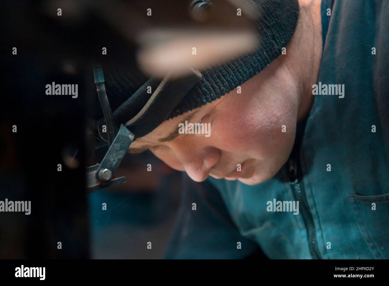 Ritratto di un saldatore ad arco in argon con un faro sulla testa sul posto di lavoro Foto Stock