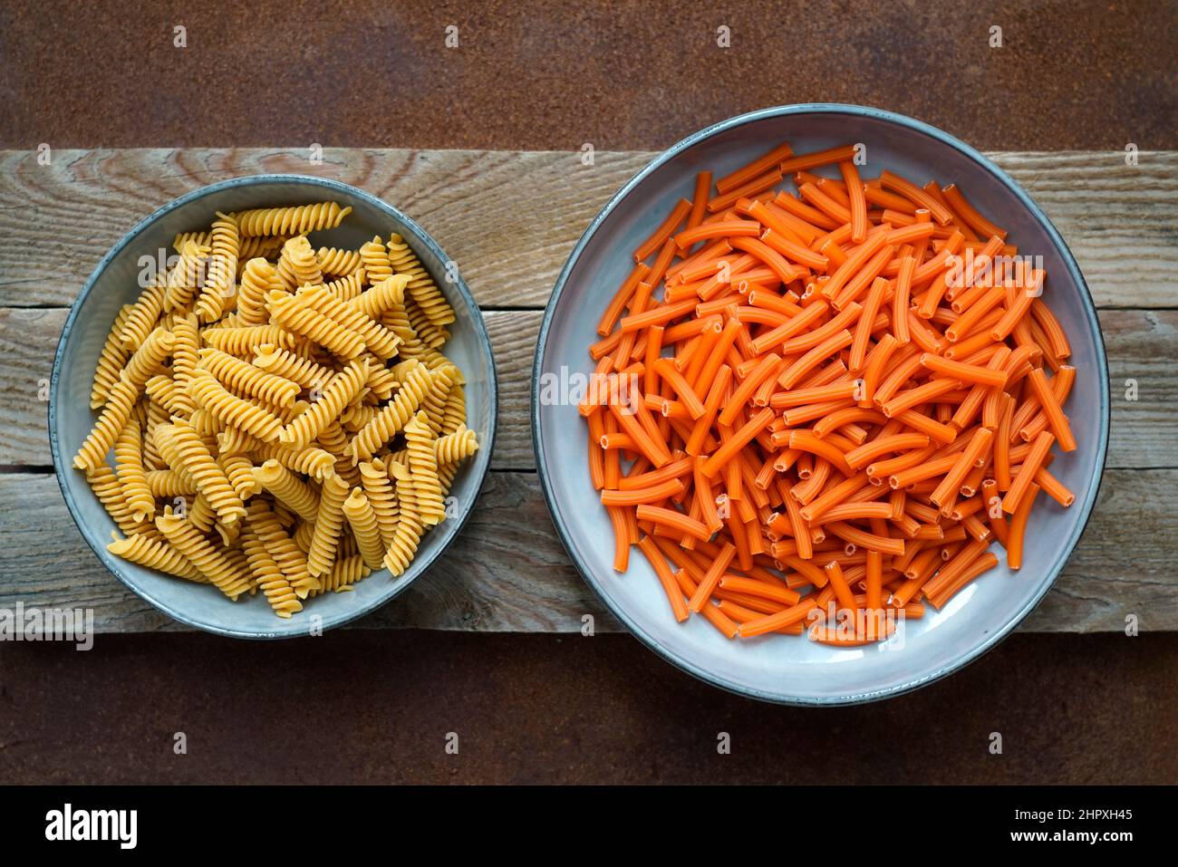 Pasta biologica a base di farina di lenticchie rosse e fusilli integrale a base di farina di ceci toscane e di riso bruno su sfondo di legno e metallo Foto Stock