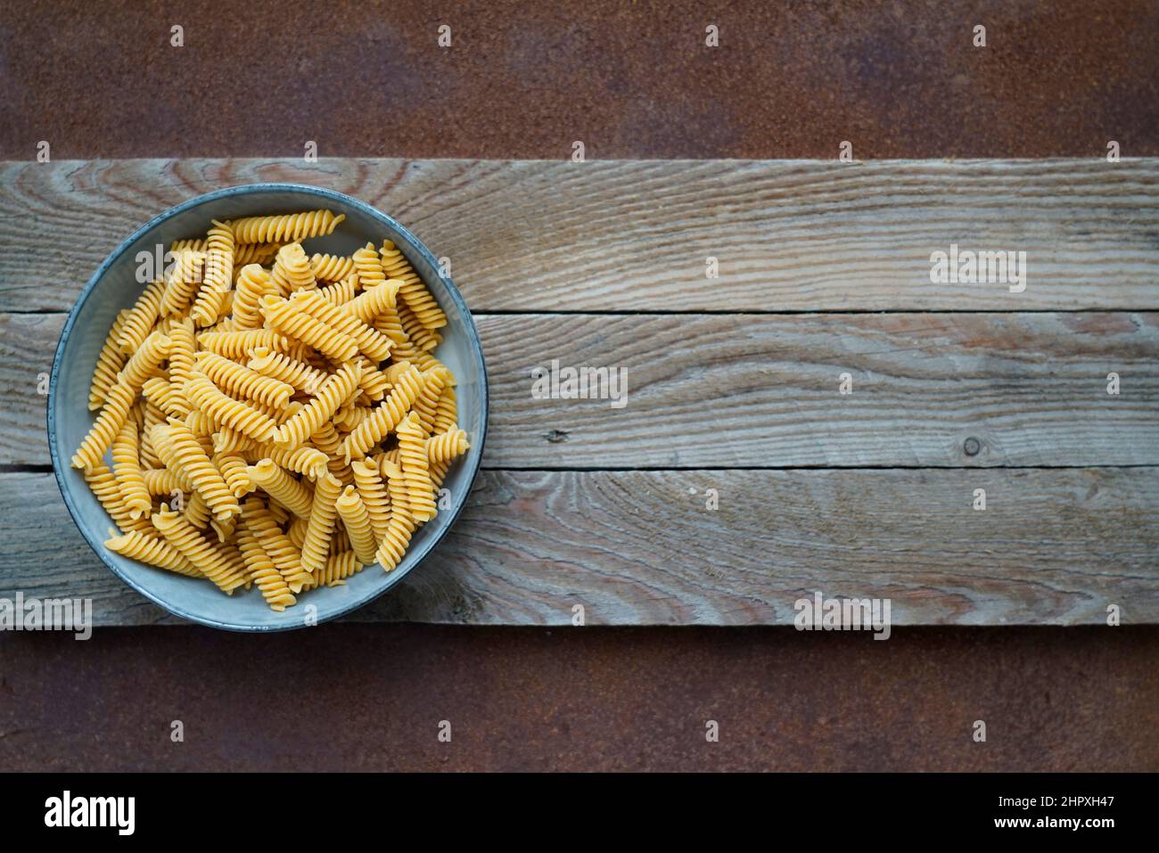Fusilli pasta integrale fatta con farina di ceci e riso bruno, su sfondo di legno e metallo con spazio per il testo, Italia, Europa Foto Stock