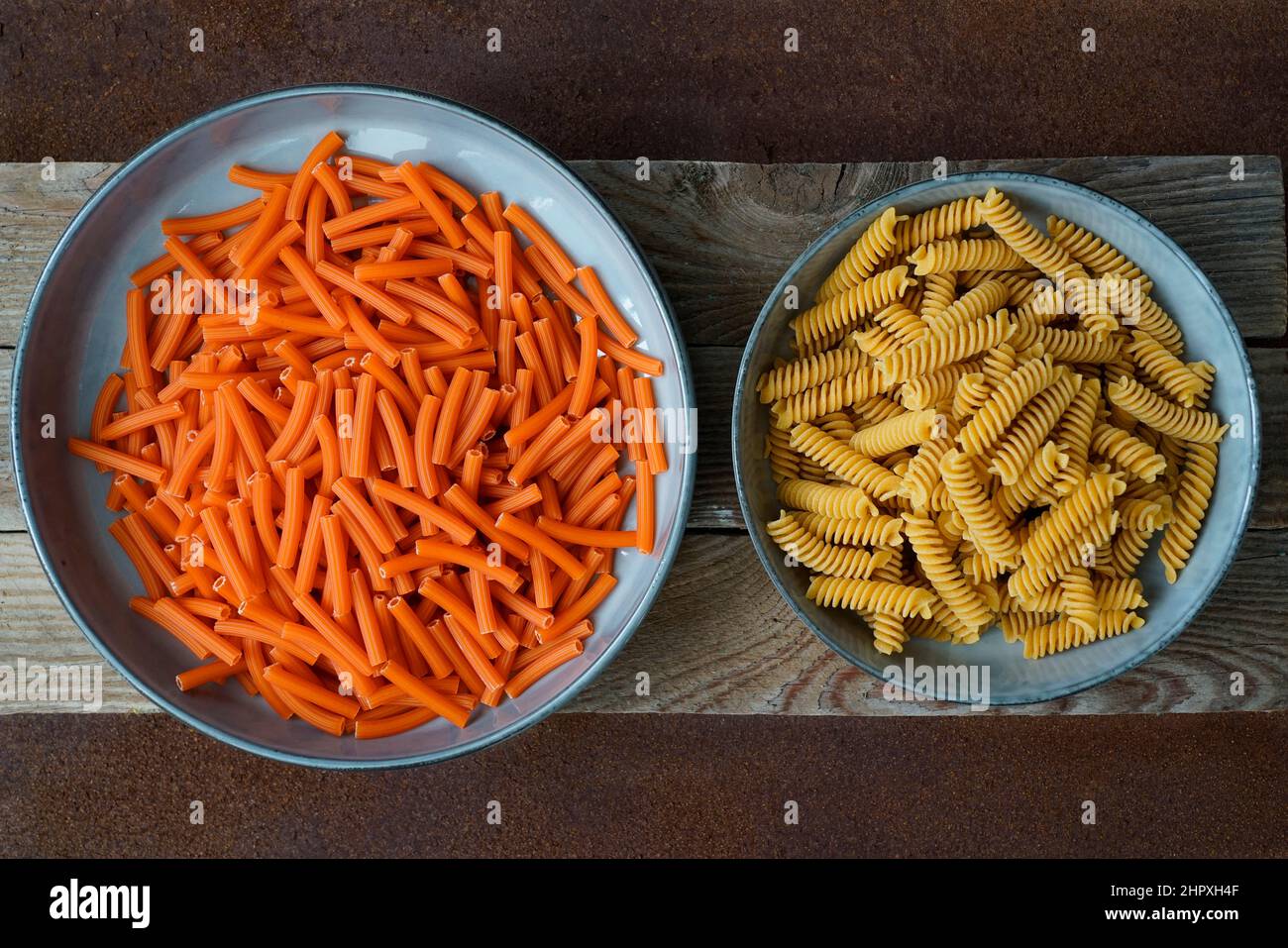 Pasta biologica a base di farina di lenticchie rosse e fusilli integrale a base di farina di ceci toscane e di riso bruno su sfondo di legno e metallo Foto Stock