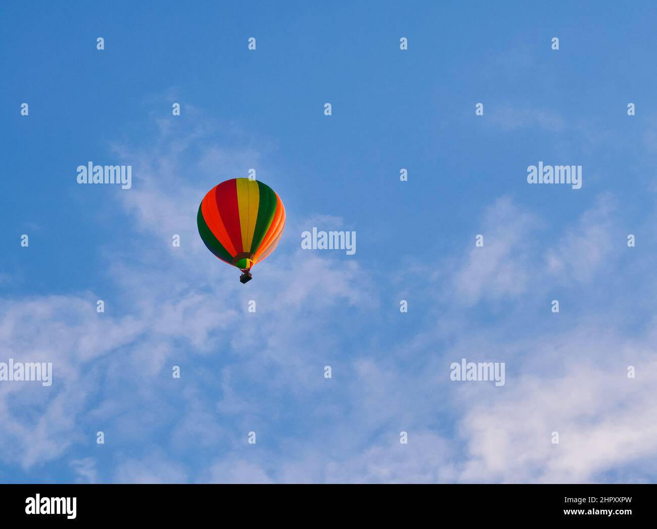 Un colorato pallone ad aria calda che vola attraverso il cielo nuvoloso Foto Stock