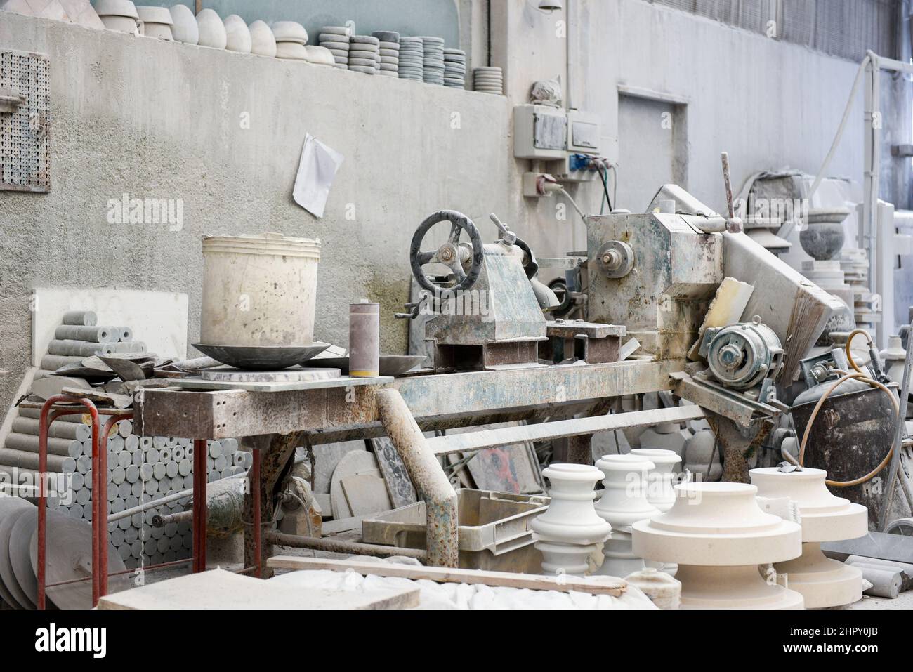 Varie costruzioni di argilla poste vicino alla macchina di produzione in officina di marmo chiaro con pareti grigie Foto Stock