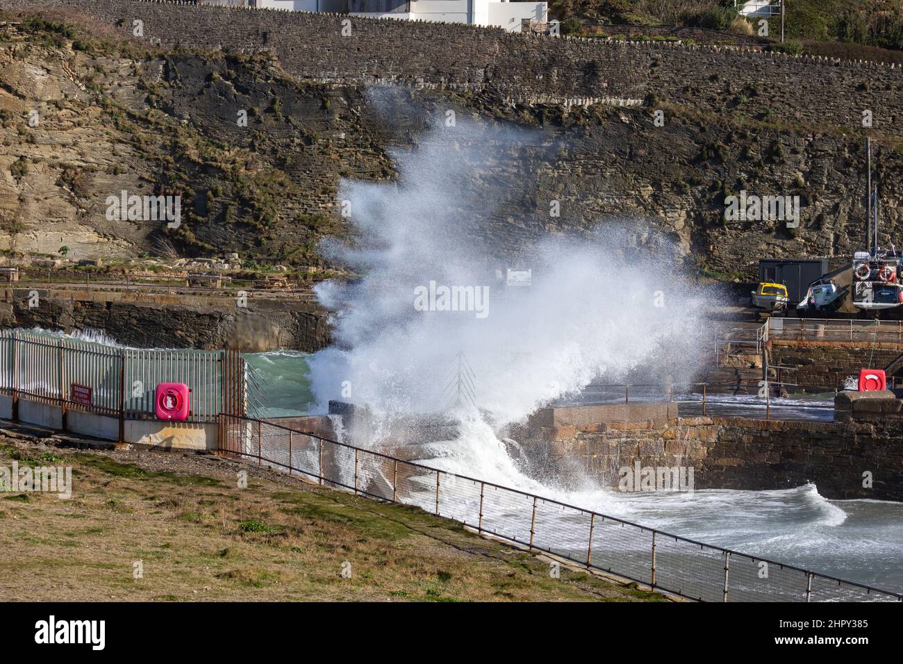 Portreath,Cornovaglia,24th Febbraio 2022,il mare spruzza sopra la capanna di Dead Mans come forti venti di 46mph con le docce di grandine ha causato grandi onde a Portreath,Cornovaglia questa mattina. La temperatura era di 7C ma con il fattore windchill si sentiva come 2C. Gli escursionisti di cani e le persone hanno ancora coraggiato una passeggiata lungo la spiaggia.Credit: Keith Larby/Alamy Live News Foto Stock