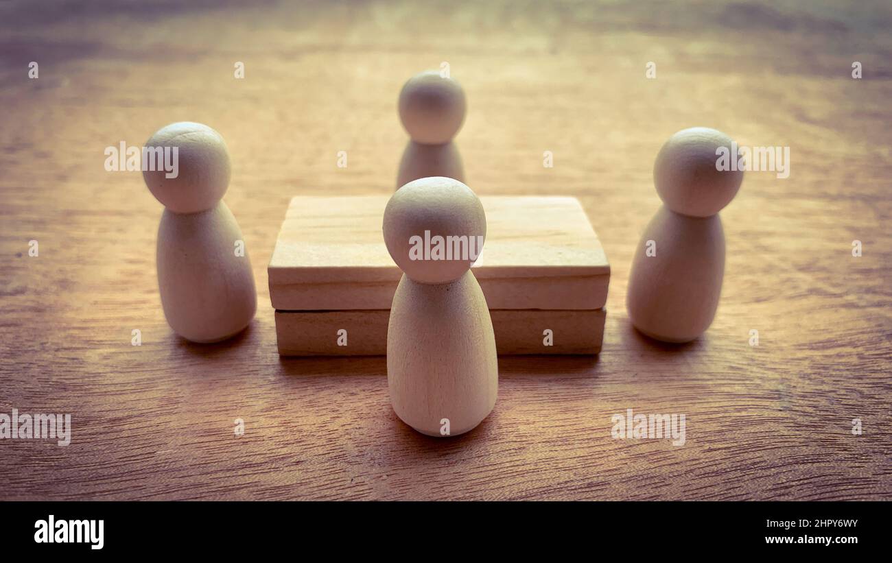 Bambole in legno che circondano un modello di tavola in legno. Concetto aziendale Foto Stock