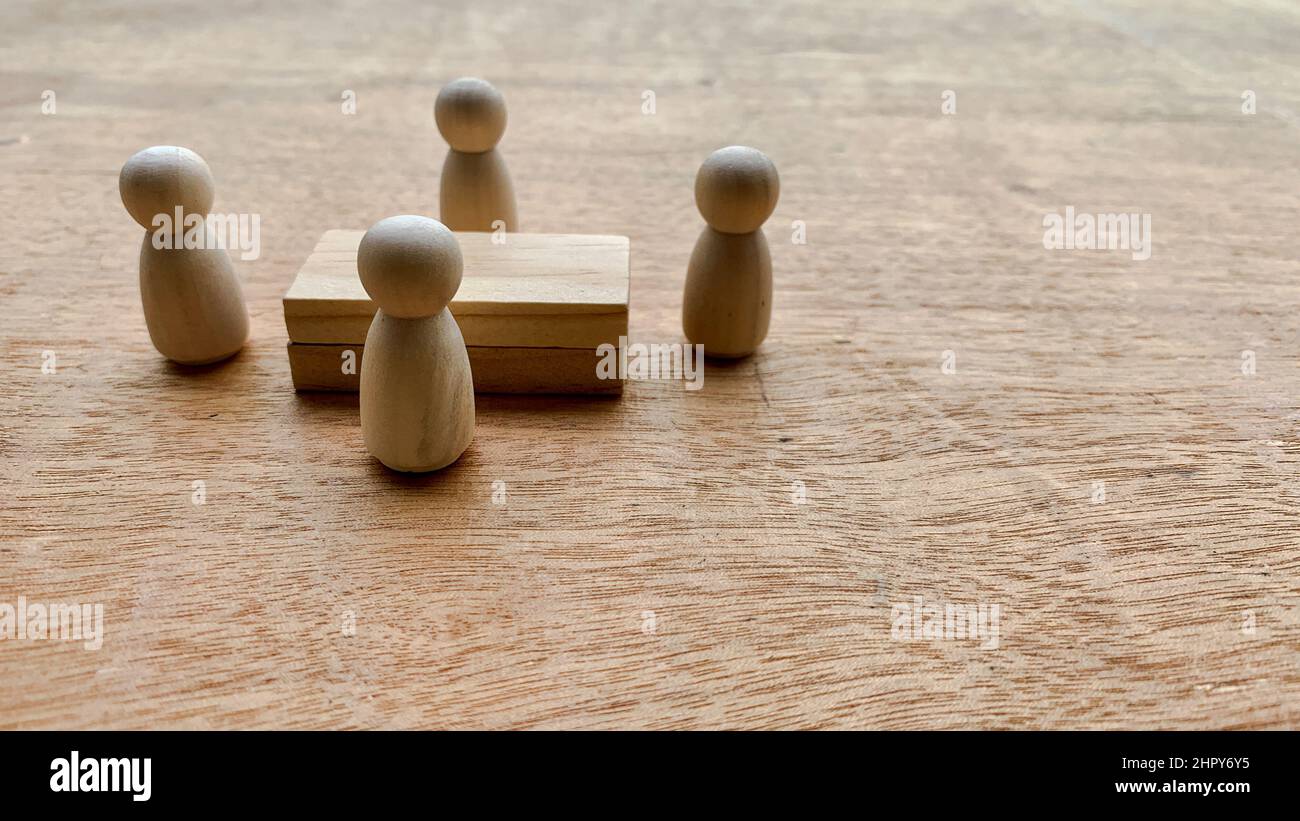 Bambole in legno che circondano un modello di tavola in legno. Concettuale Foto Stock