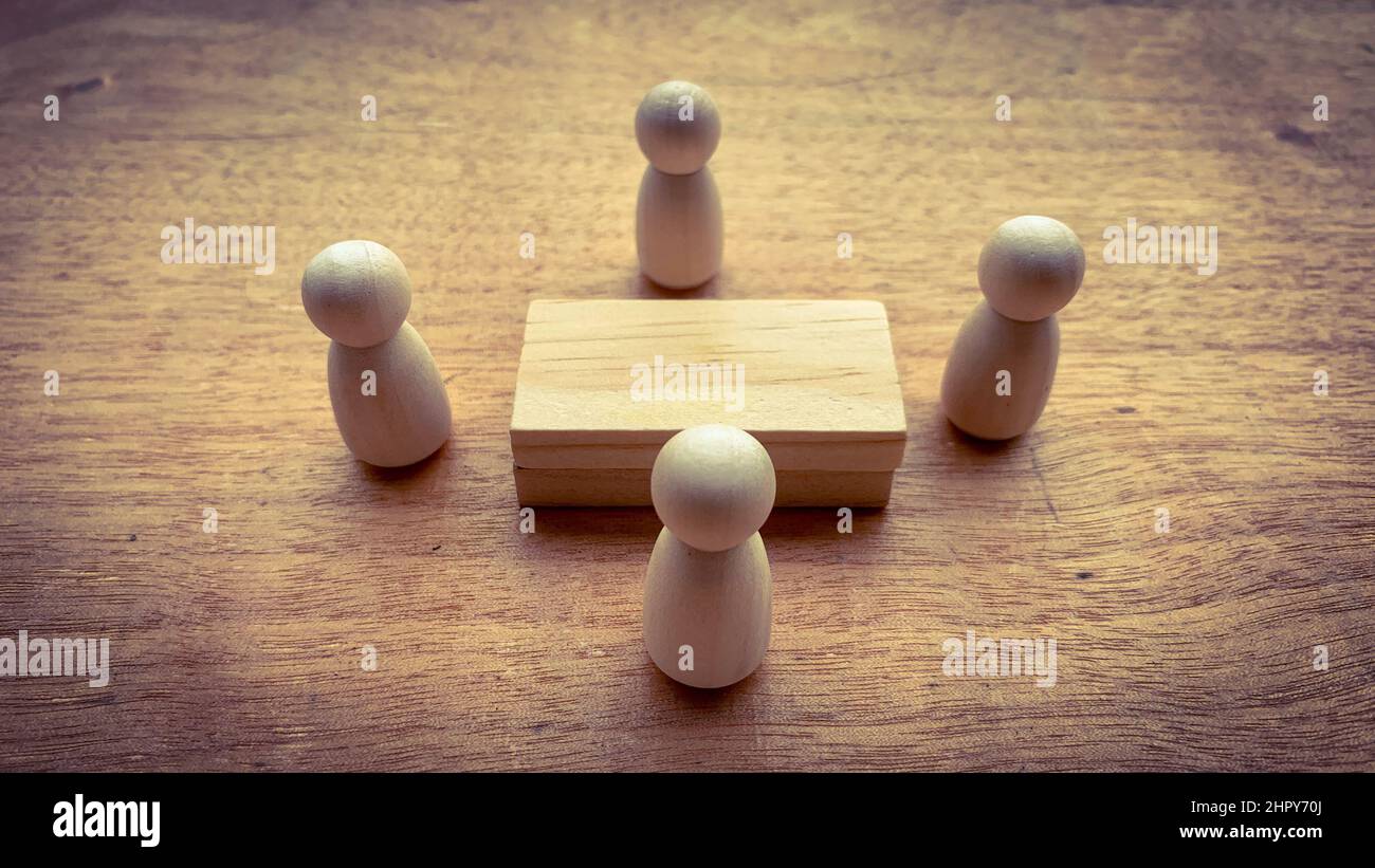 Bambole in legno che circondano un modello di tavola in legno. Concetto aziendale Foto Stock