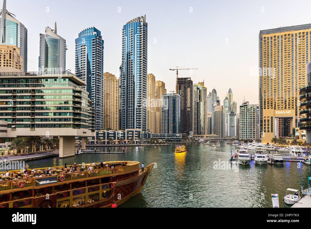 I turisti possono godersi una crociera in barca tradizionale dhow lungo la moderna Marina di Dubai, circondata da grattacieli, ristoranti e yacht club di lusso. Foto Stock