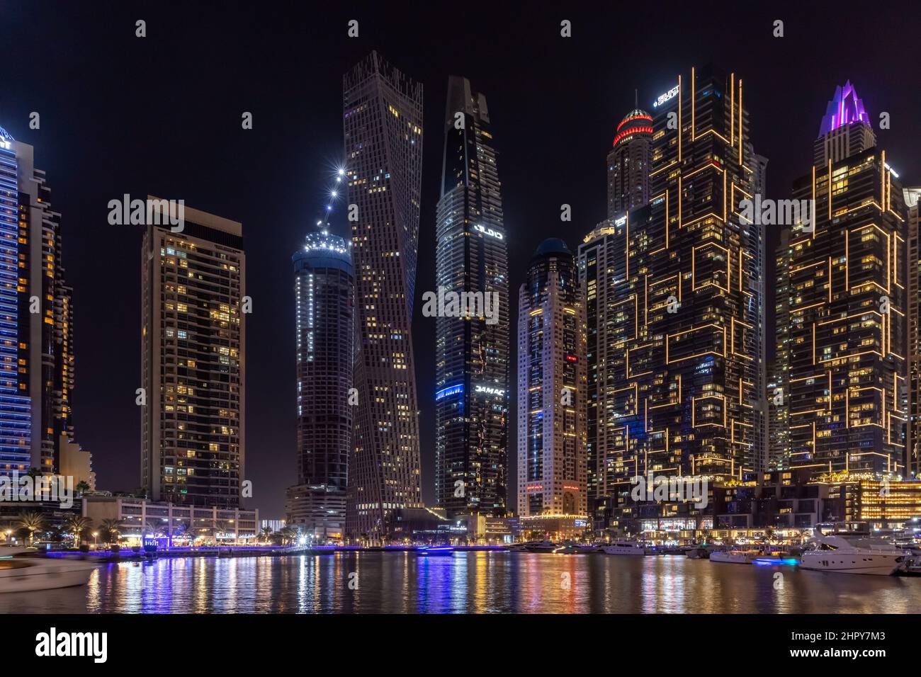 Skyline di grattacieli di notte, con grattacieli, barche e riflessi in acqua, nel quartiere Marina di Dubai, Emirati Arabi Uniti. Foto Stock