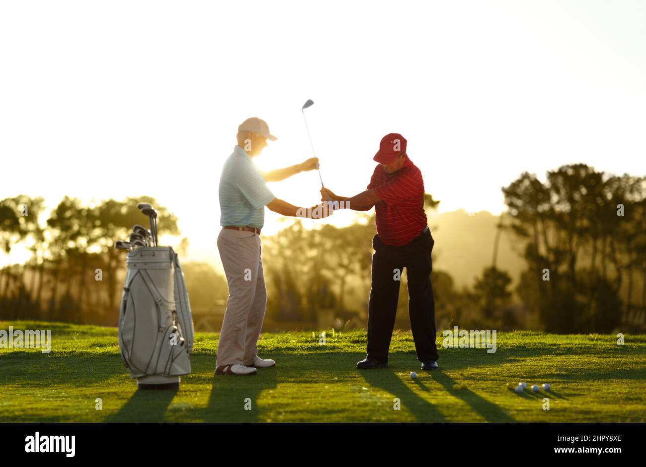 Mantenga il livello del randello a destra attraverso il vostro swing. Un golfer maschio che riceve l'aiuto dal suo caddy sul campo da golf. Foto Stock