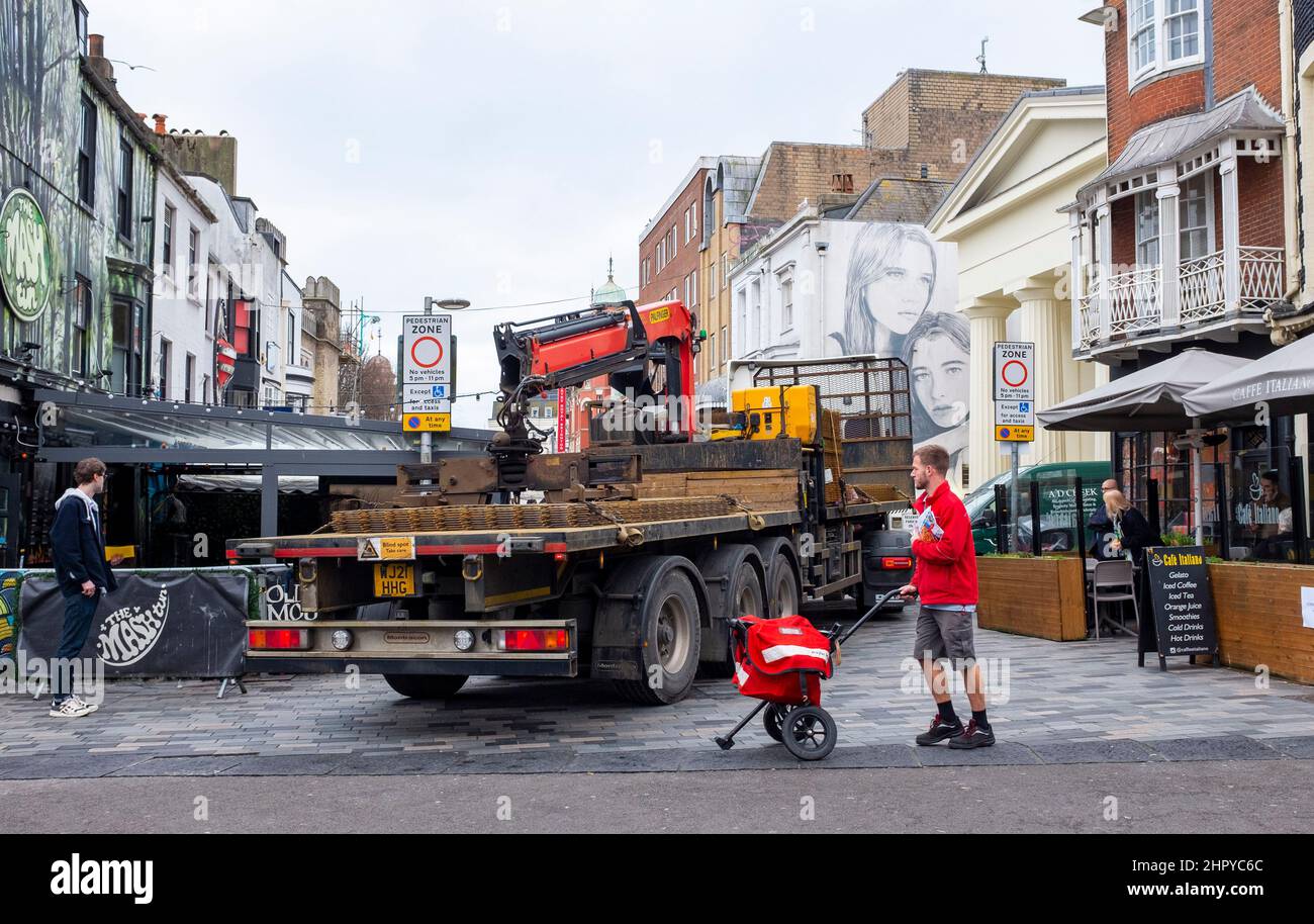 Un camion si trasforma in New Road Brighton mentre il lavoratore di consegna della posta reale cammina vicino Foto Stock